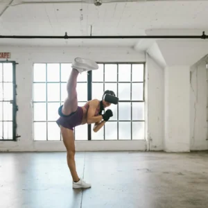 Woman using VR headset for fitness training. Full shot in an industrial-style studio.